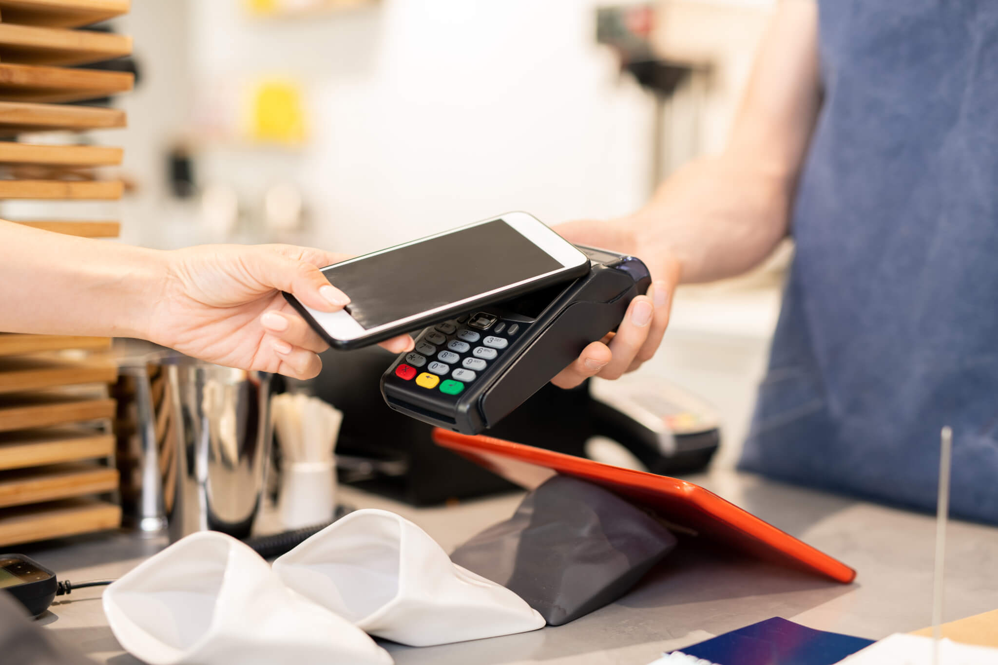 Hand of young woman holding smartphone close to electronic payment machine ERP: Financial Solutions